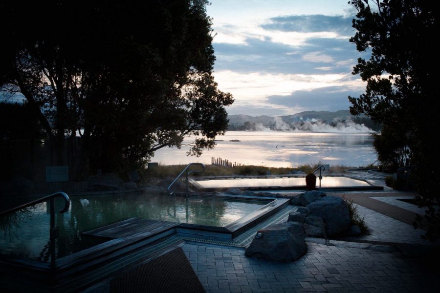 A person relaxing on a hot pool while on front of a steaming lake.