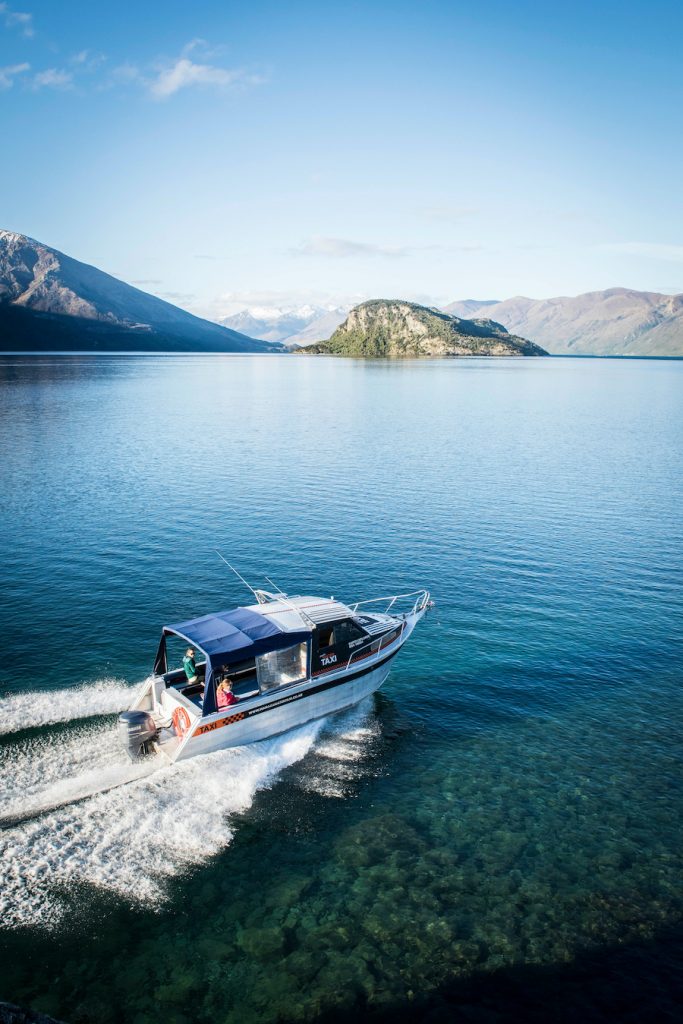 A small yacht cruising its way on the calm lake.