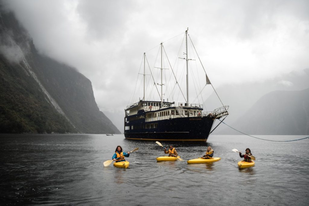 Milford Mariner on Milford Sound, with kayakers in the water.